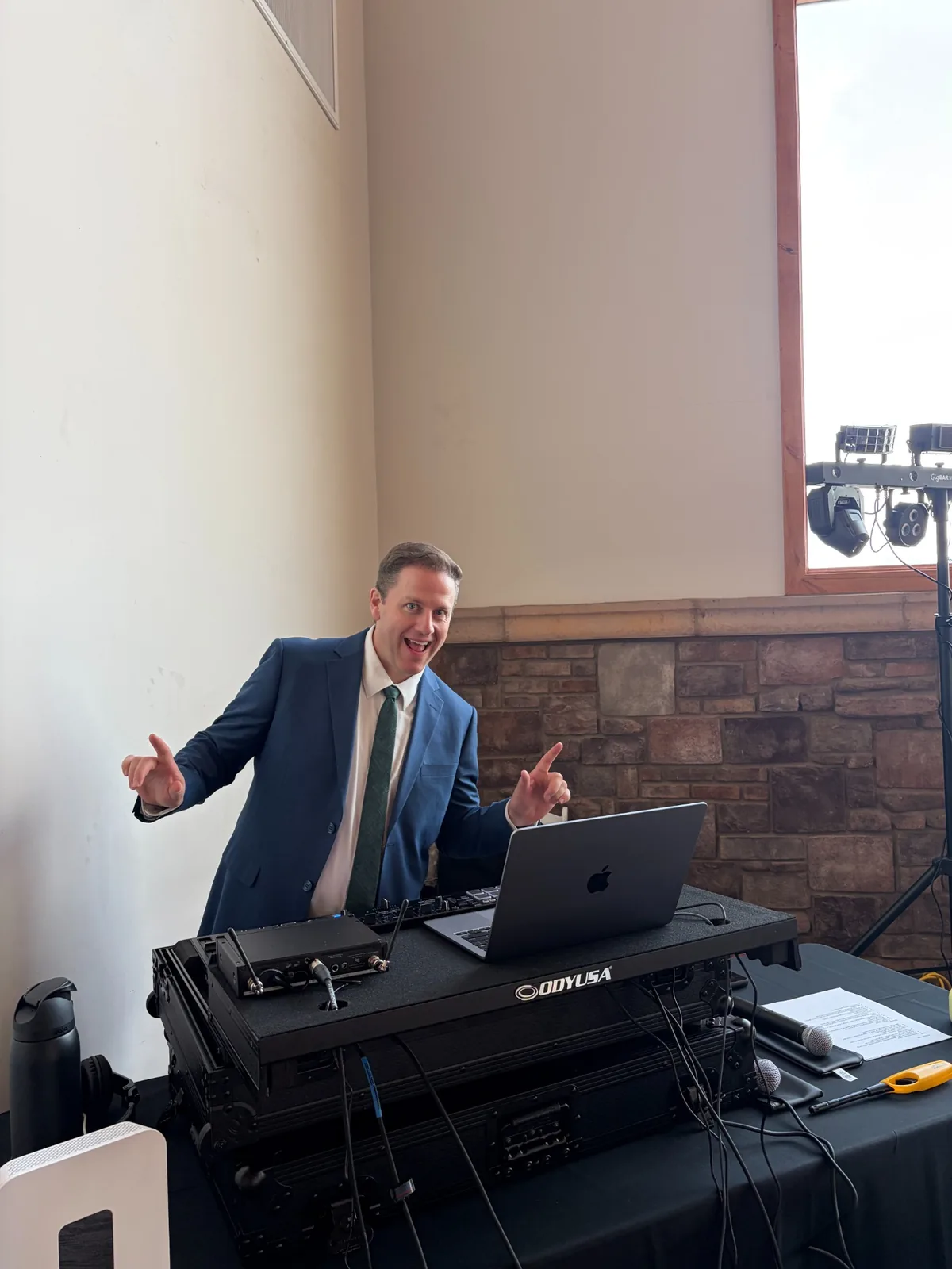 Andrew Taylor in a navy suit behind the Odyssey DJ booth